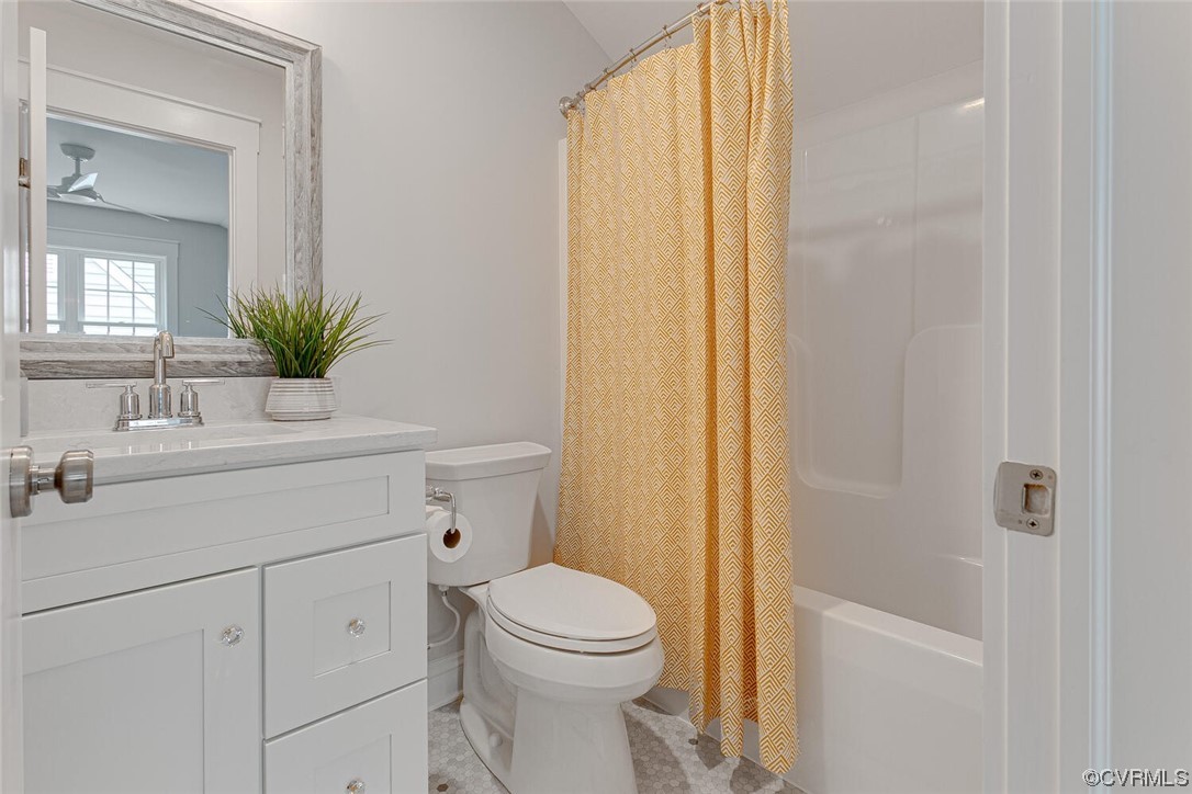 Bathroom with a white vanity, toilet, and bathtub behind a mustard patterned shower curtain.