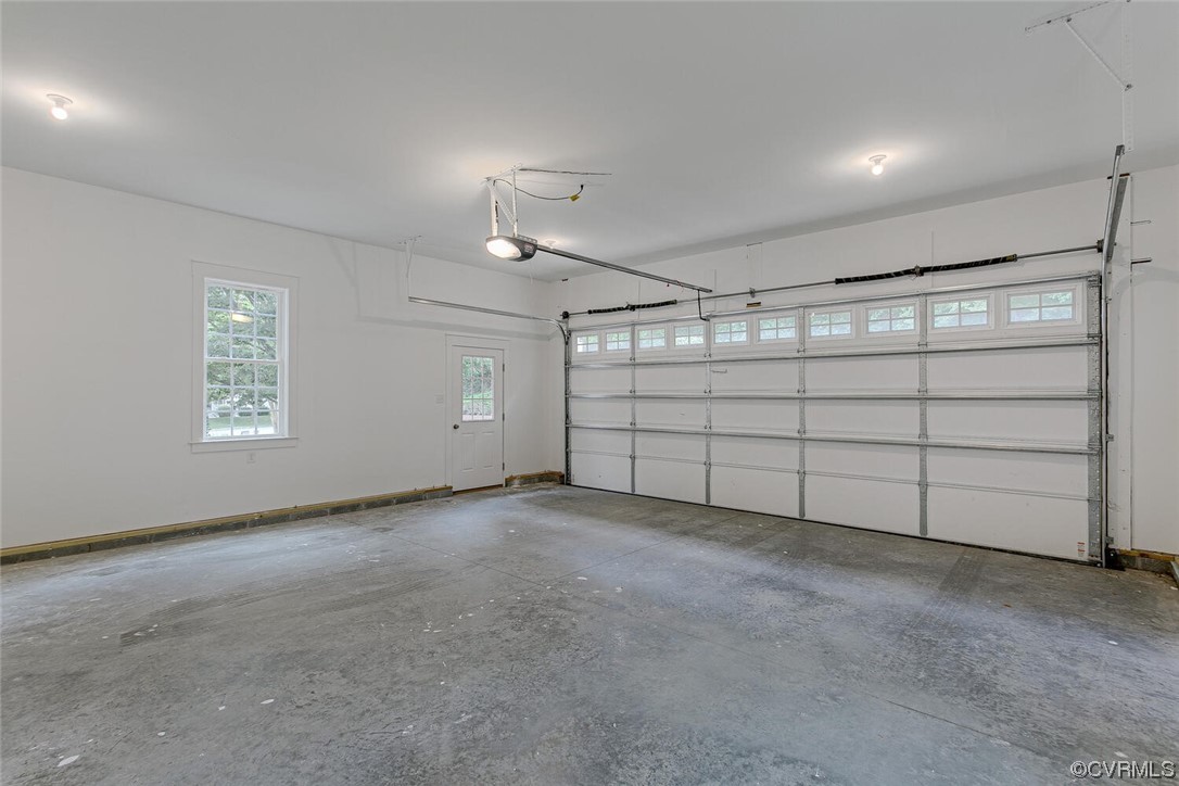 Empty garage with a wide double door, concrete floor, and windows above the door.