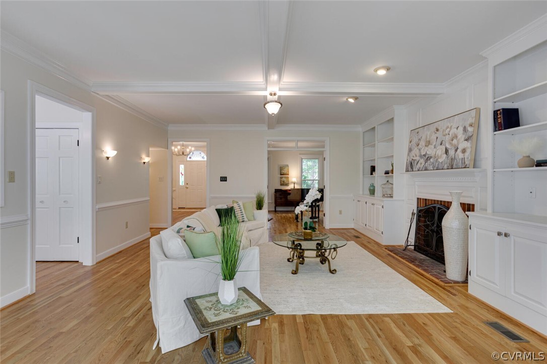 Living room with hardwood floors, white fireplace, built-in shelves, and a large area rug.