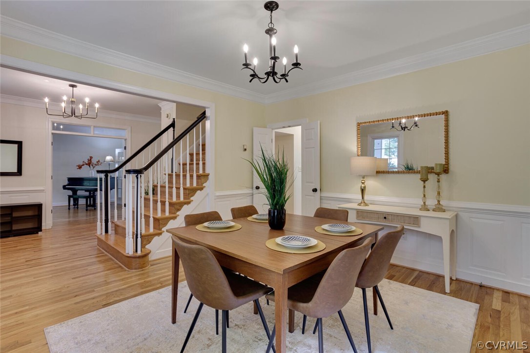 Furnished dining room with a wooden table, chandelier, and staircase with white balusters.