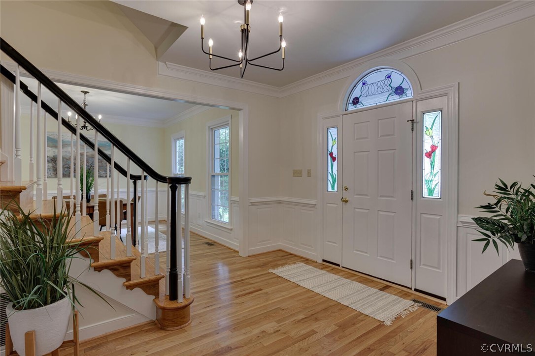 Entry foyer with hardwood floors, a staircase, and a front door with stained-glass panels.