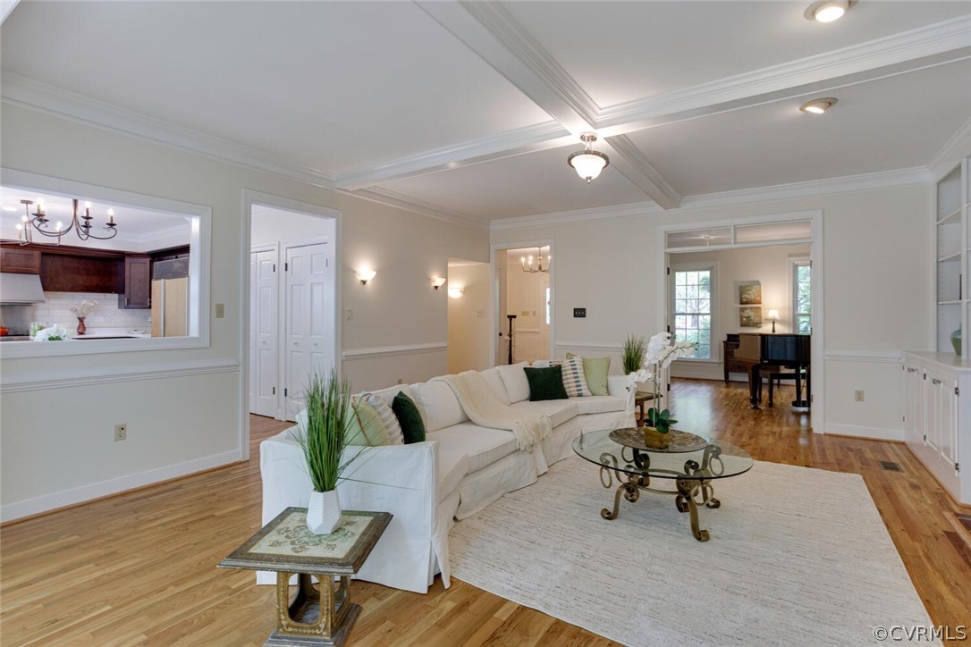 Staged living room with a white sectional, glass coffee table, and coffered ceiling.