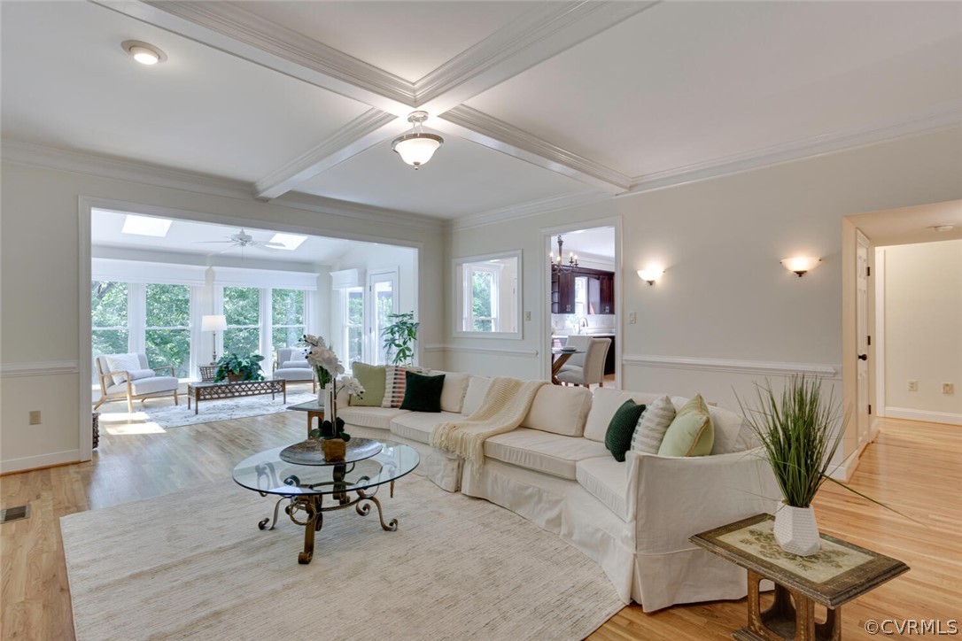Living room with a cream sectional, coffered ceiling, and bright windowed sitting area.