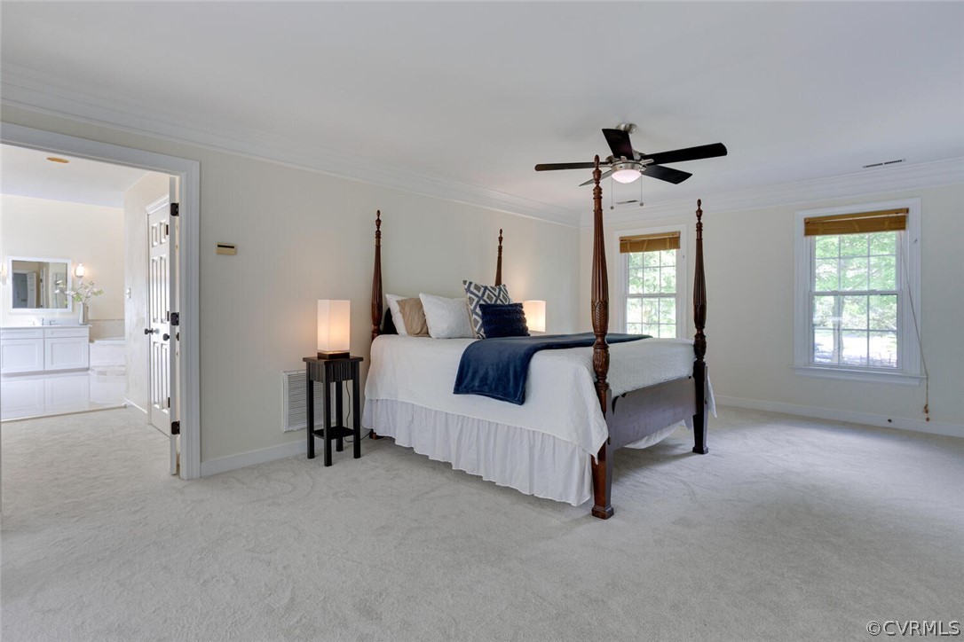 Primary bedroom with a dark wood four-poster bed, navy throw, and doorway to a bright bathroom.
