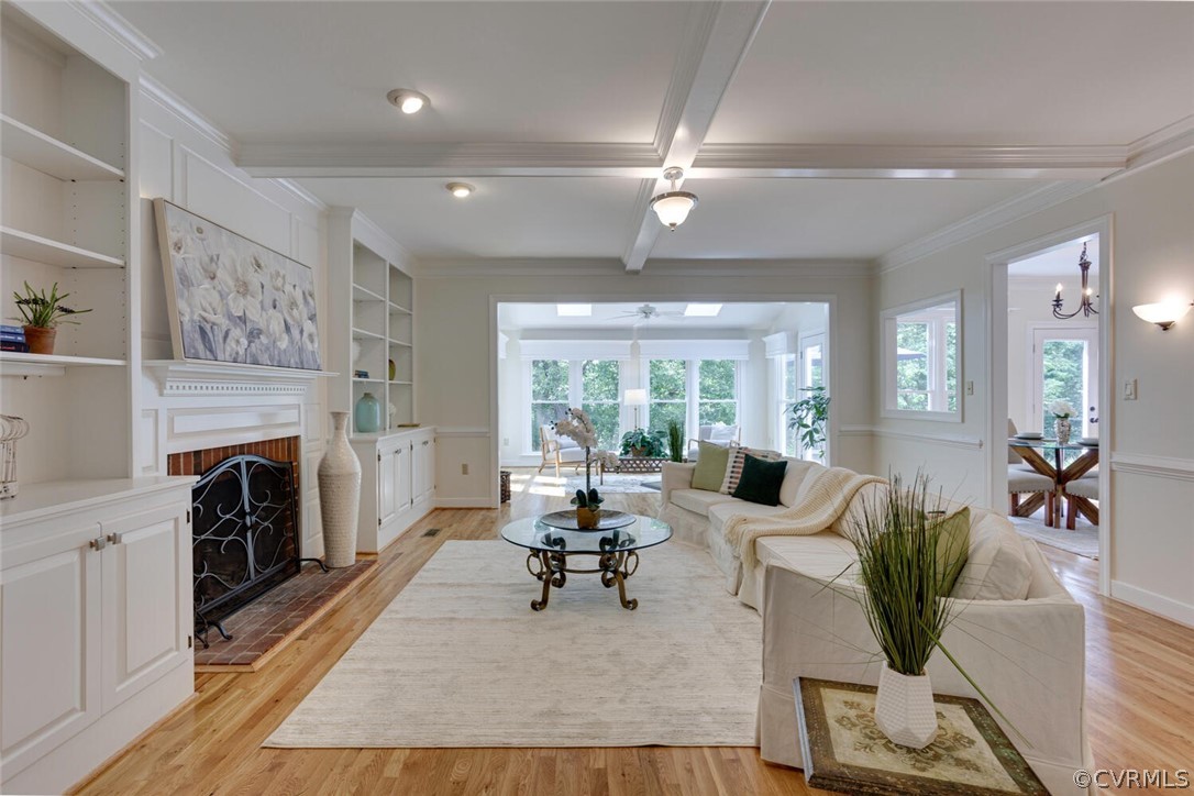 Living room with white built-ins and fireplace, coffered ceiling, and a bright windowed sitting area.