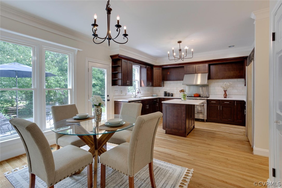 Kitchen with dark wood cabinets, central island, stainless steel range, and a window-side dining area.