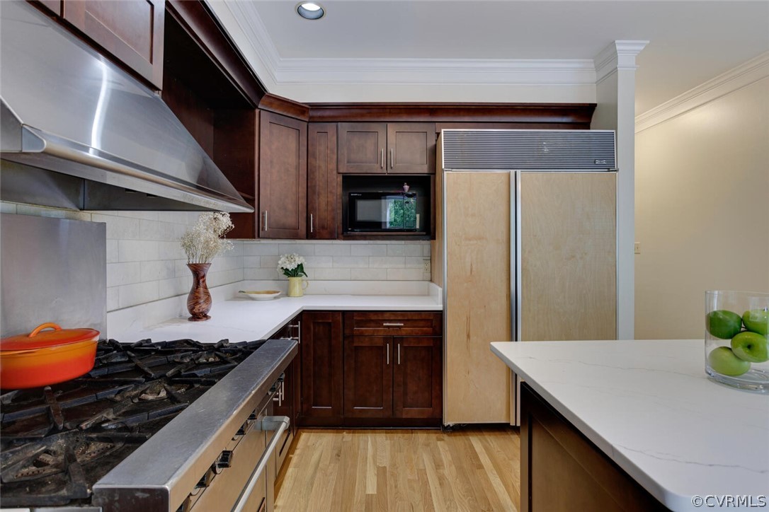 Kitchen with dark wood cabinetry, a gas cooktop, and a large refrigerator.