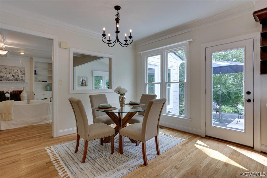 Dining room with a glass-top table, four upholstered chairs, hardwood floors, and windows beside a patio door.