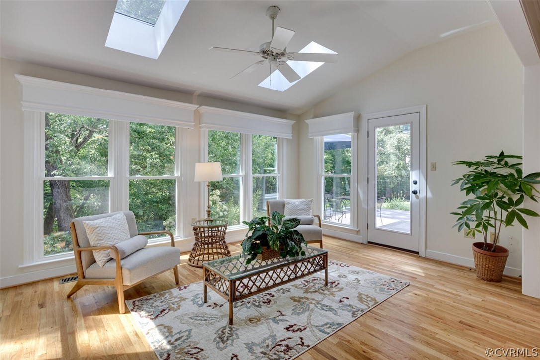 Bright sitting room with wide windows, a skylight, and a glass door to the patio.