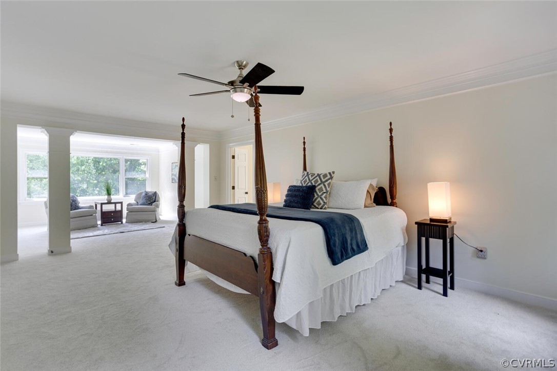Bedroom with a dark wood four-poster bed and a bright window-side sitting area.