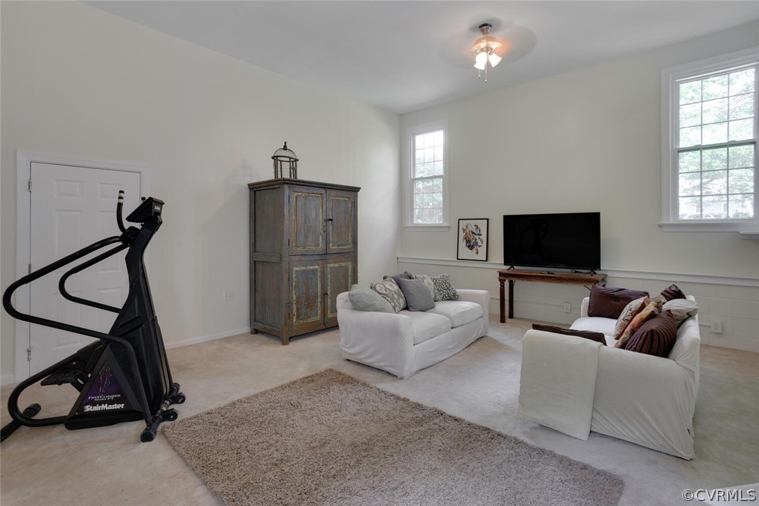 Living room with white sofas, tall windows, a television, and a stair-climbing machine.