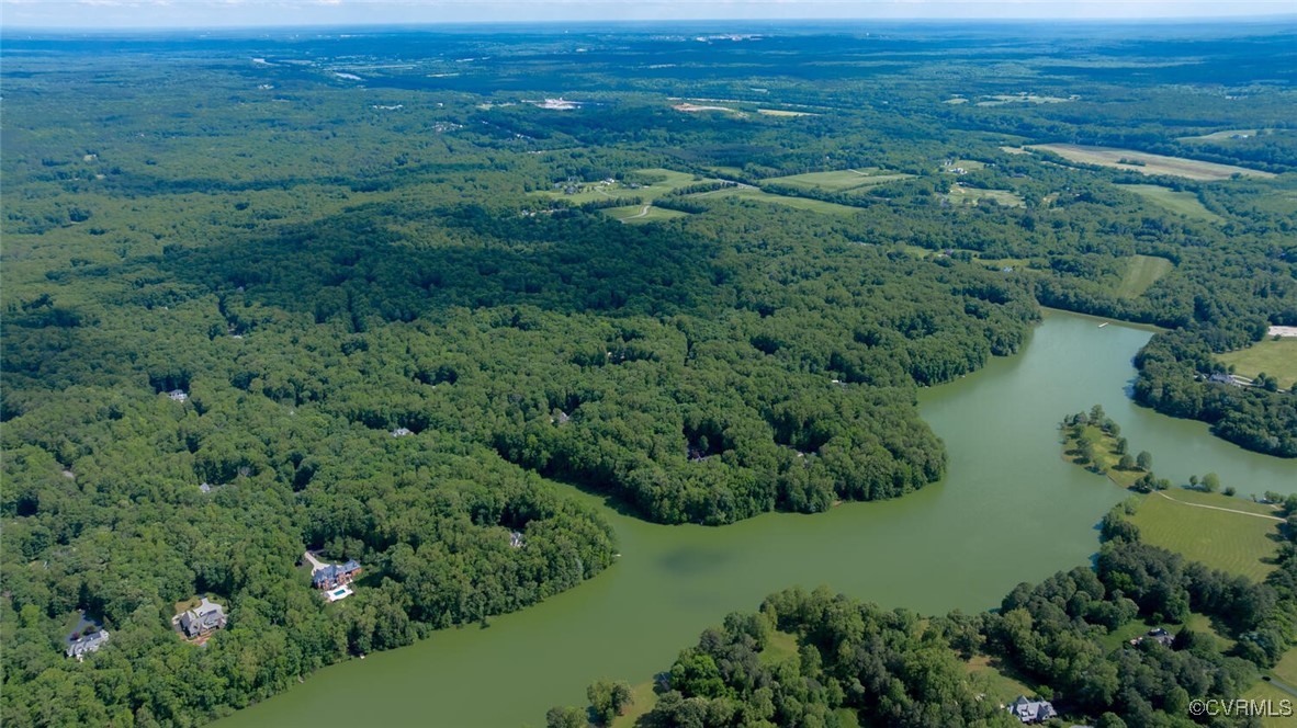 Aerial view of wooded homes along a broad waterway, with countryside stretching to the horizon.
