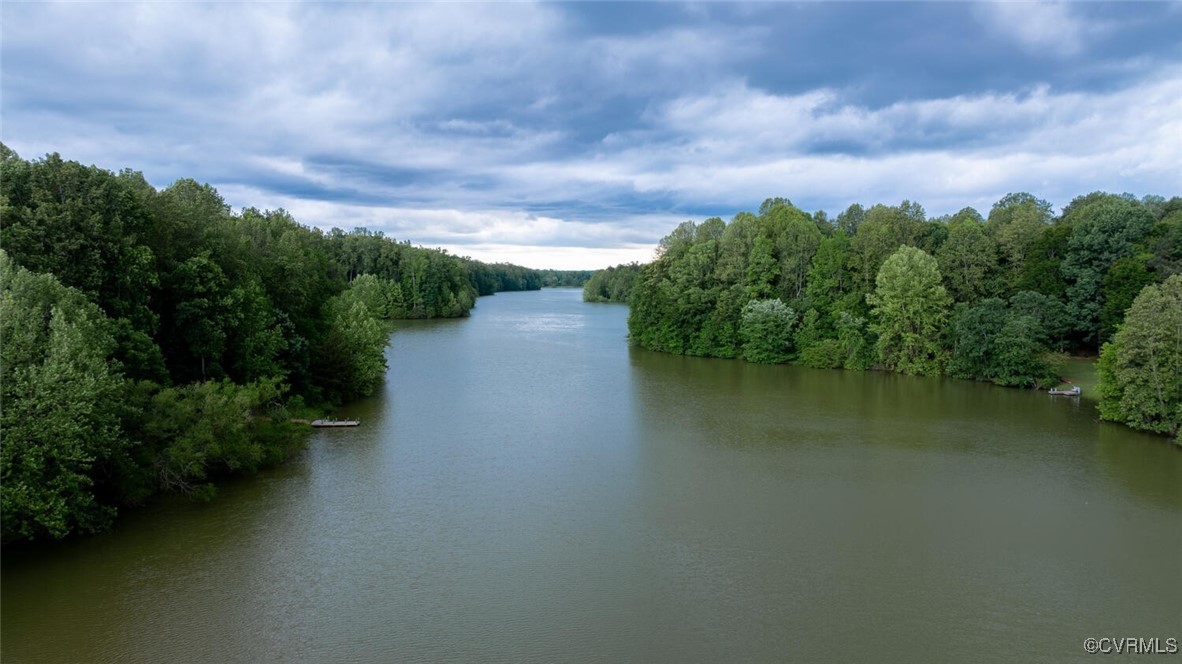 Lake bordered by dense green trees, with small docks along the shoreline.