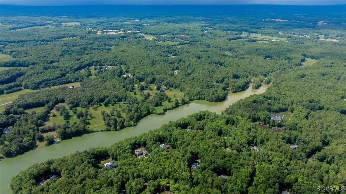 A winding river meanders through wooded countryside, with open fields and scattered homes.