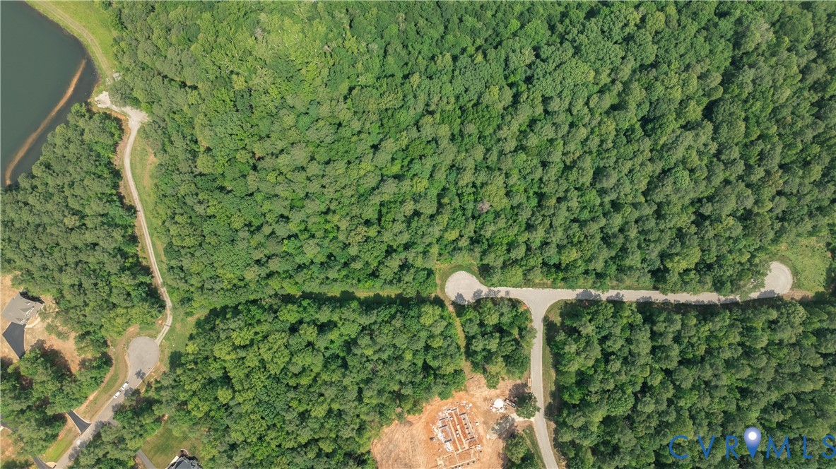 Aerial view of wooded land beside a lake, with roads and a construction foundation.