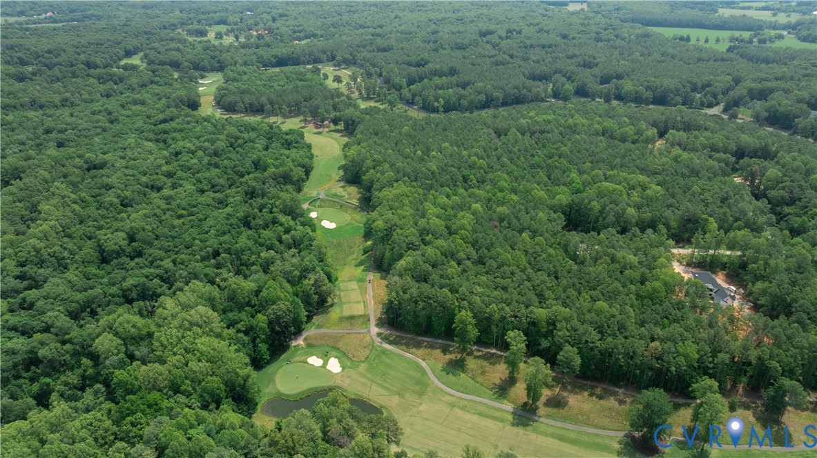 Aerial golf course surrounded by dense woods, with sand bunkers and small ponds.