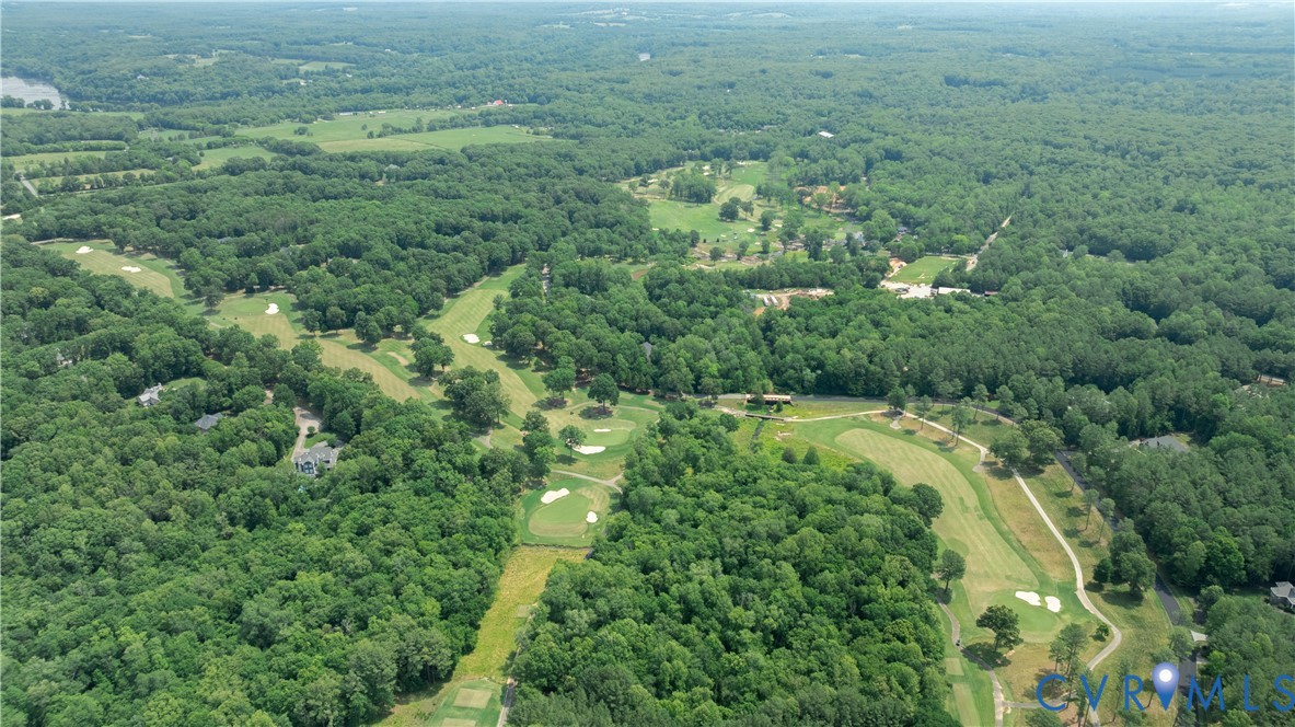 Aerial view of a golf course surrounded by dense woodland, with winding fairways and sand bunkers.