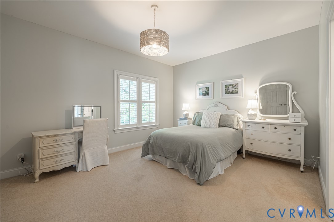 Bedroom with a gray bed, white vanity and dressers, and a large shuttered window.