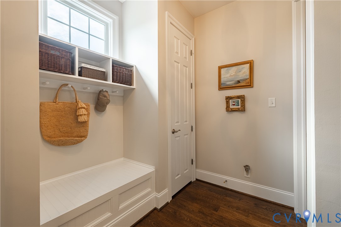 Mudroom with a built-in white bench, basket-filled cubbies, hooks, and a large window.