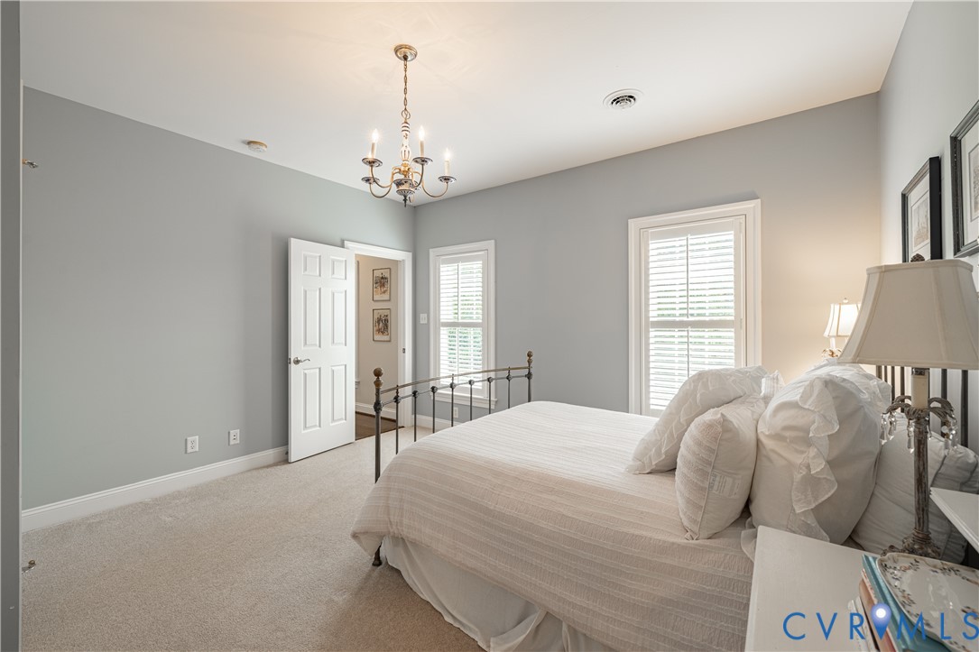 Furnished bedroom with gray walls, a white bed, and two windows with blinds.