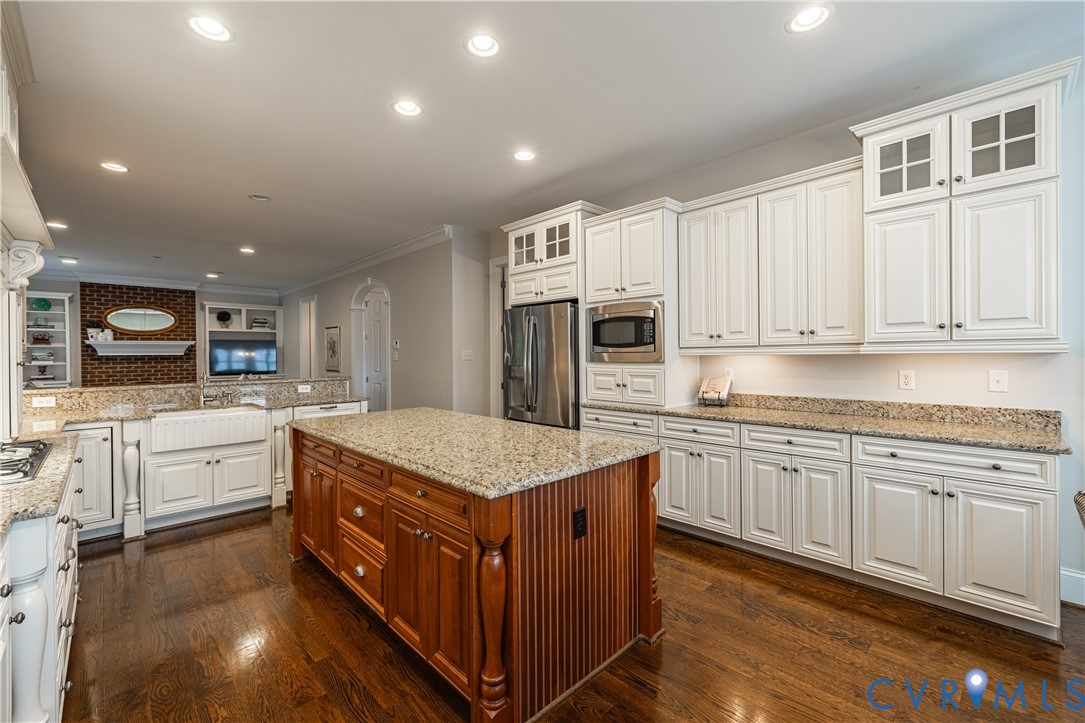 Bright kitchen with white cabinetry, granite counters, a wood island, and stainless-steel appliances.