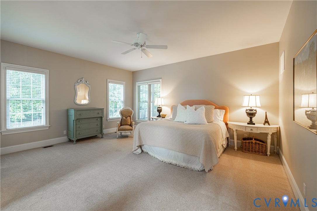 Staged bedroom with a large bed, green dresser, and windows with blinds.