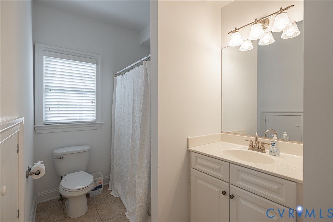 Bathroom with a white vanity, large mirror, and window beside the shower.