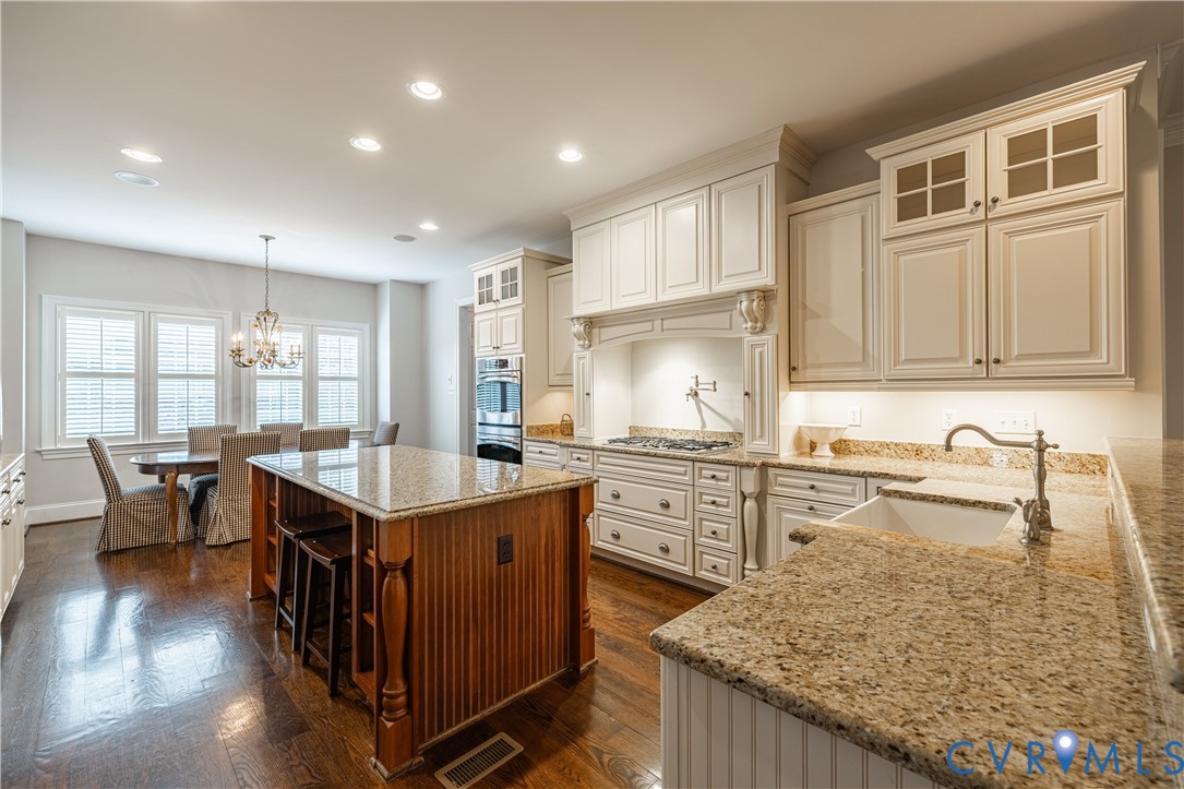 Kitchen with cream cabinetry, granite counters, a wood-paneled island, and an adjoining dining area.