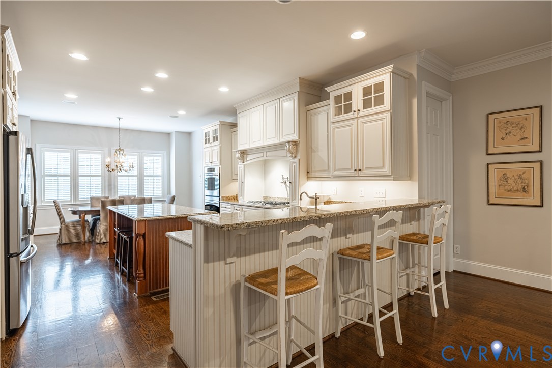 Kitchen with white cabinetry, granite breakfast bar, and dining area by shuttered windows.