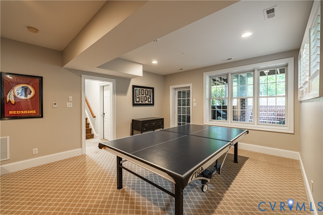 Recreation room with a table tennis table, patterned carpet, and large windows.