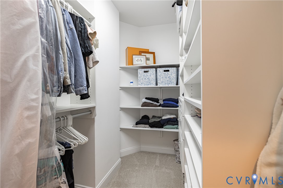 Walk-in closet with built-in shelves, hanging clothes, and folded garments.