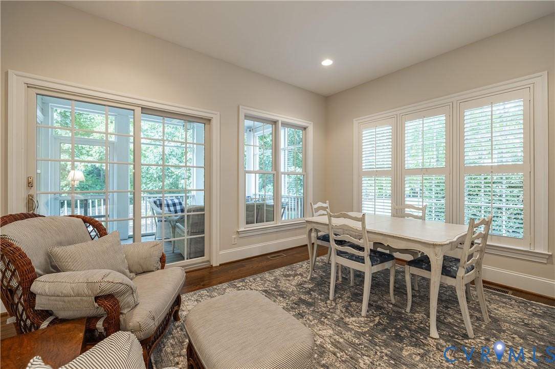 Dining room with a white table by shuttered windows and glass doors to a screened porch.