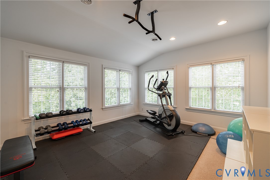 Home gym with an elliptical, dumbbell rack, rubber flooring, and several large windows.