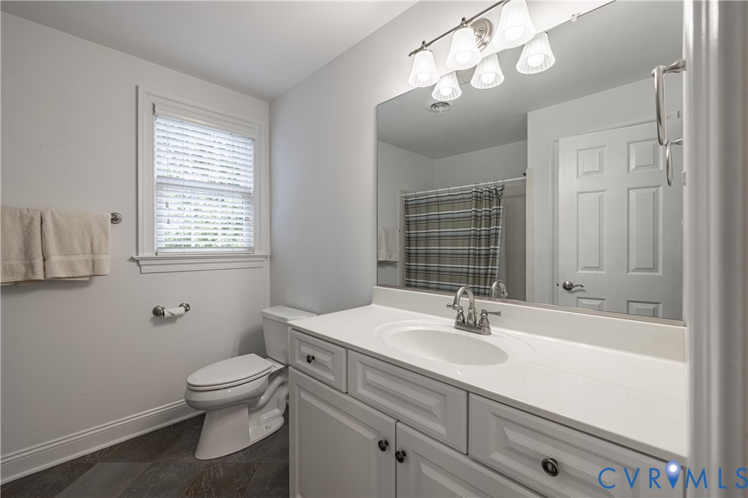 Bathroom with a white vanity, large mirror, window with blinds, and striped shower curtain.