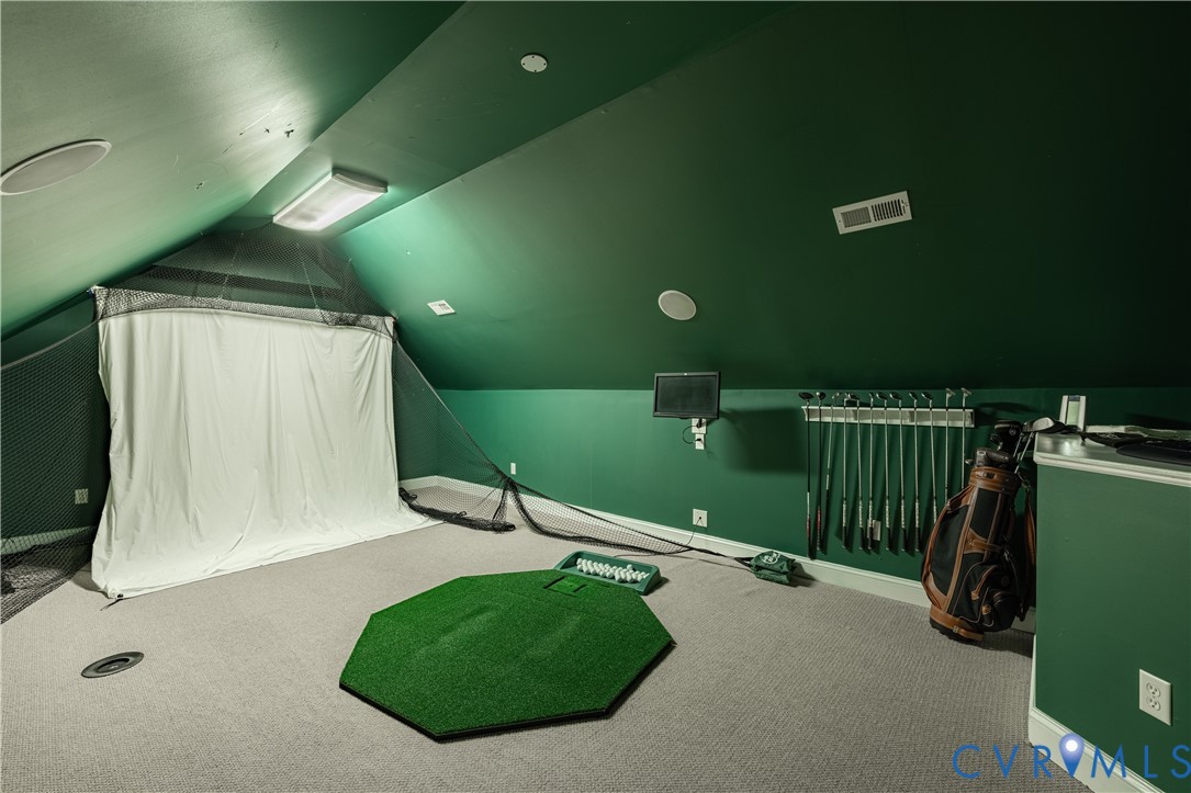 Indoor golf practice room with a hitting net, putting mat, and golf clubs.