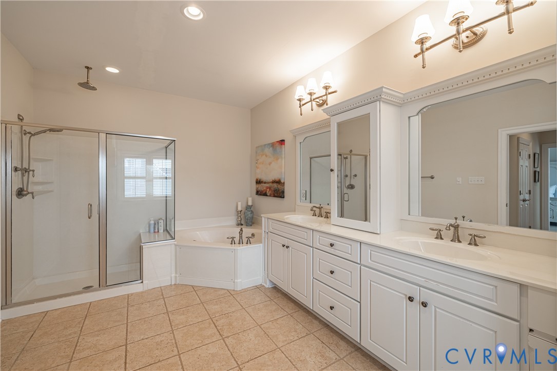 Primary bathroom with glass shower, corner soaking tub, and long double-sink vanity.