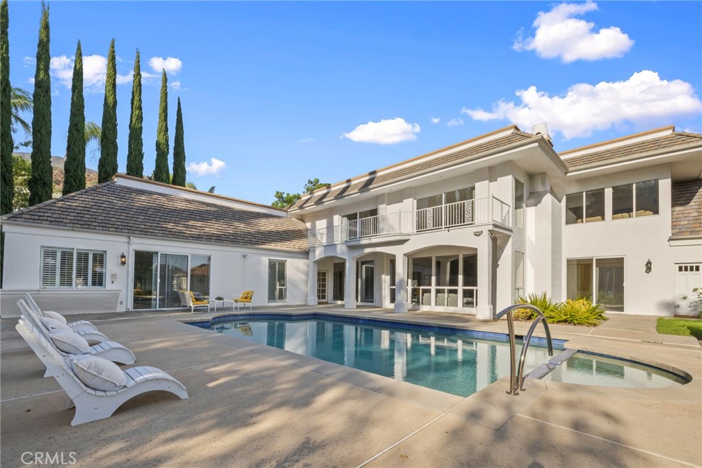 Rear exterior of a white two-story house with a large pool and curved balcony.