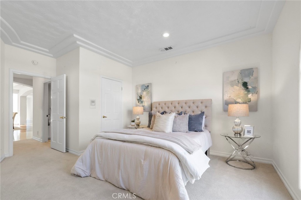 Staged bedroom with a tufted headboard, layered pillows, matching lamps, and abstract wall art.
