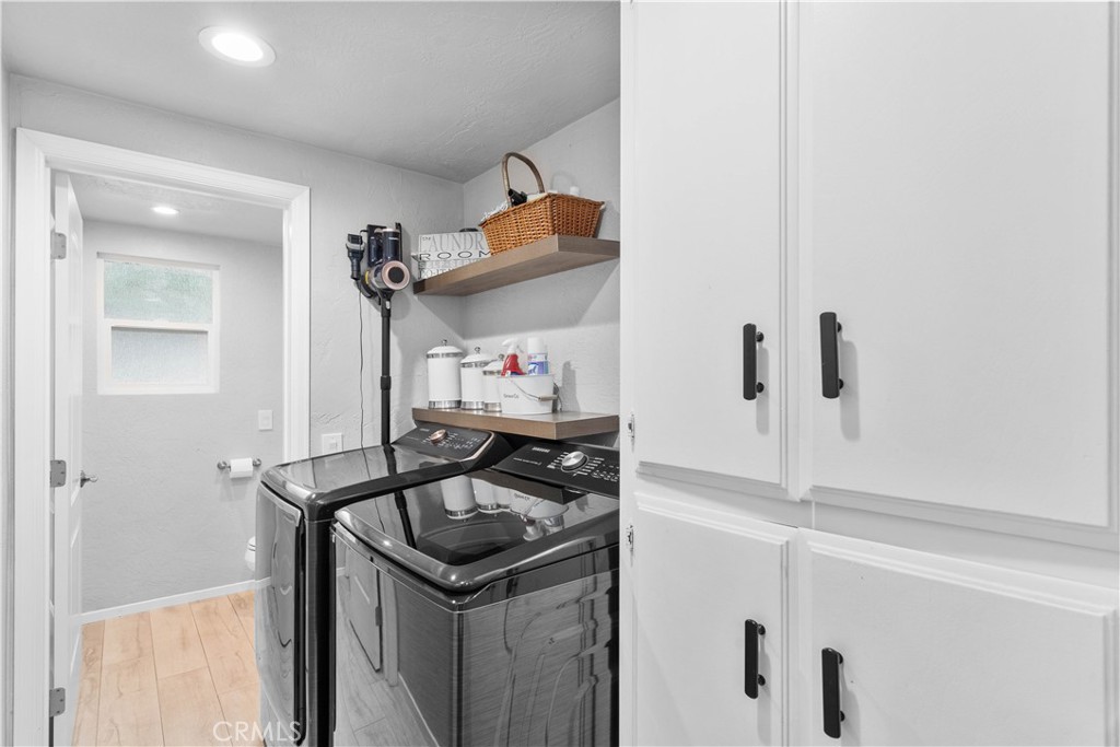 Laundry room with a washer and dryer, white built-in cabinets, and a shelf with a woven basket.