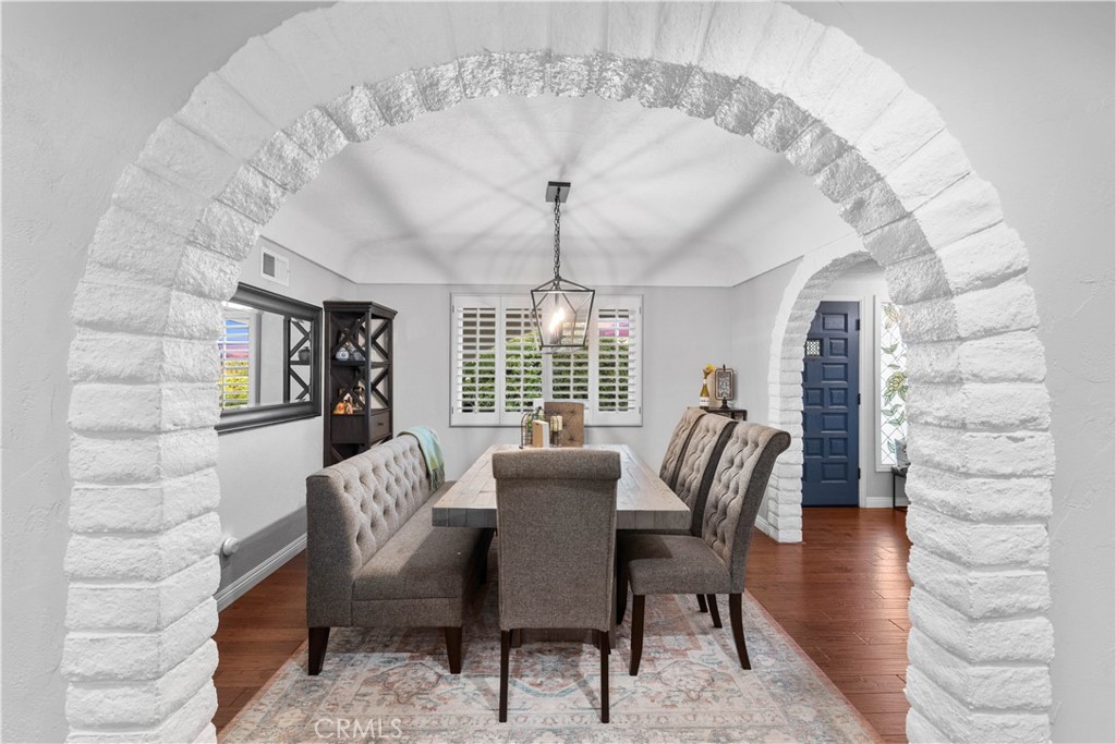 Dining room framed by a white stone arch, with a wood table and upholstered chairs.