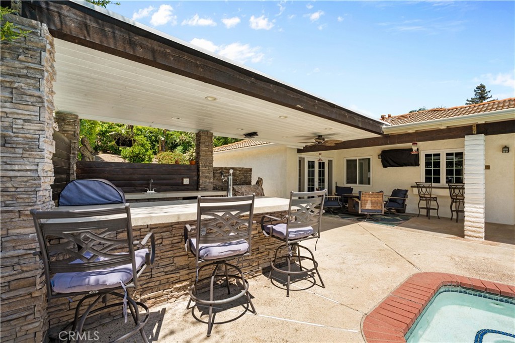 Covered patio with stone bar seating beside a swimming pool.