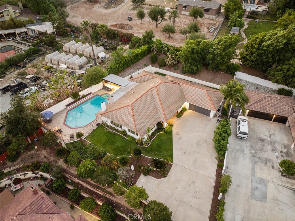 Aerial view of a tiled-roof home with a backyard pool and landscaped grounds.