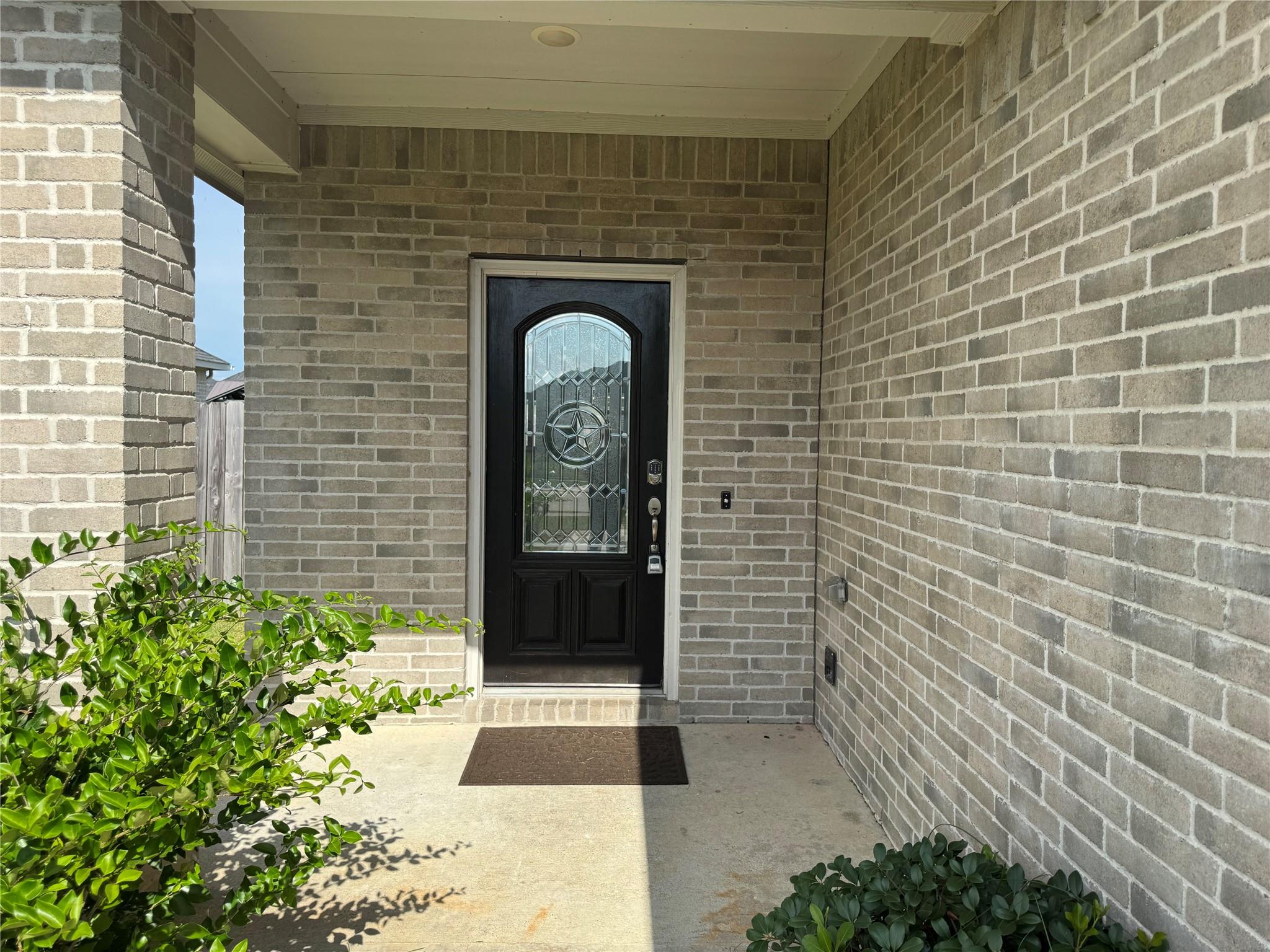 Covered brick entry with a black front door featuring decorative glass and a star design.