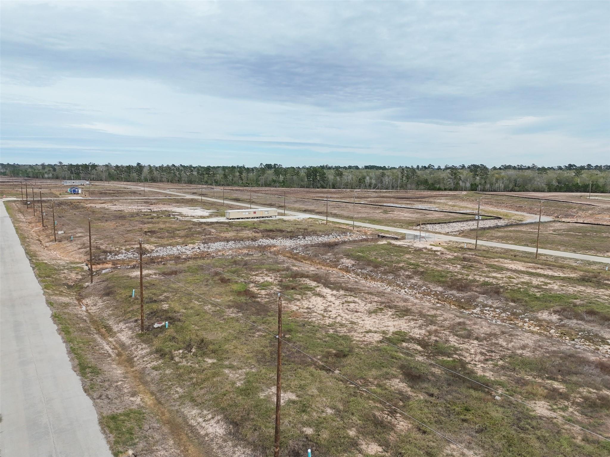 Aerial view of cleared subdivision lots with utility poles, drainage swales, and paved roads.