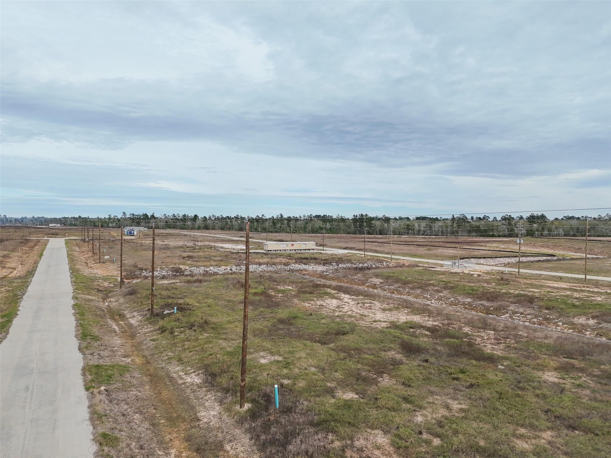 Vacant land beside a paved road, with utility poles and open grassy lots.