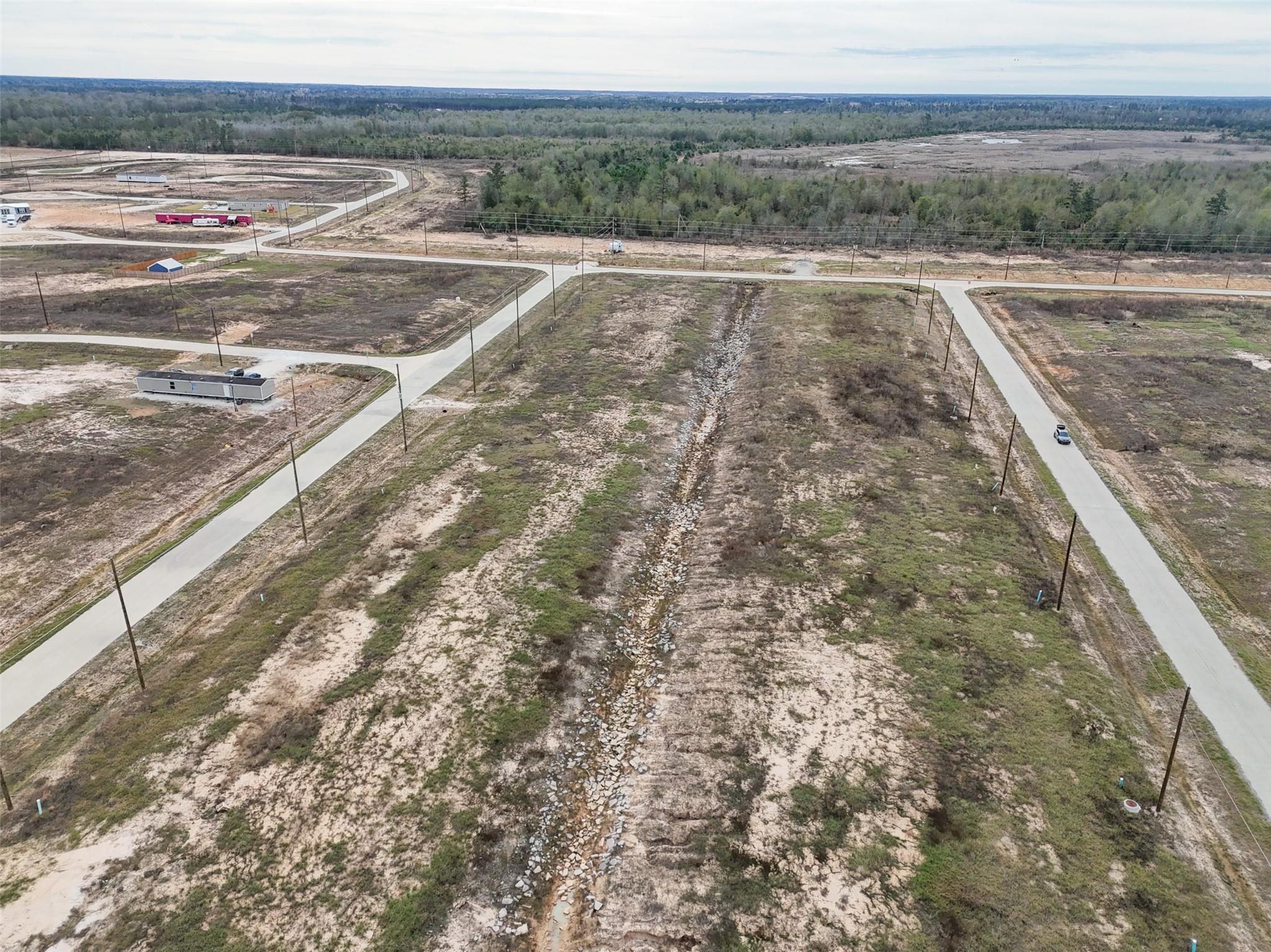 Aerial view of vacant lots with paved roads and a rock-lined drainage ditch.