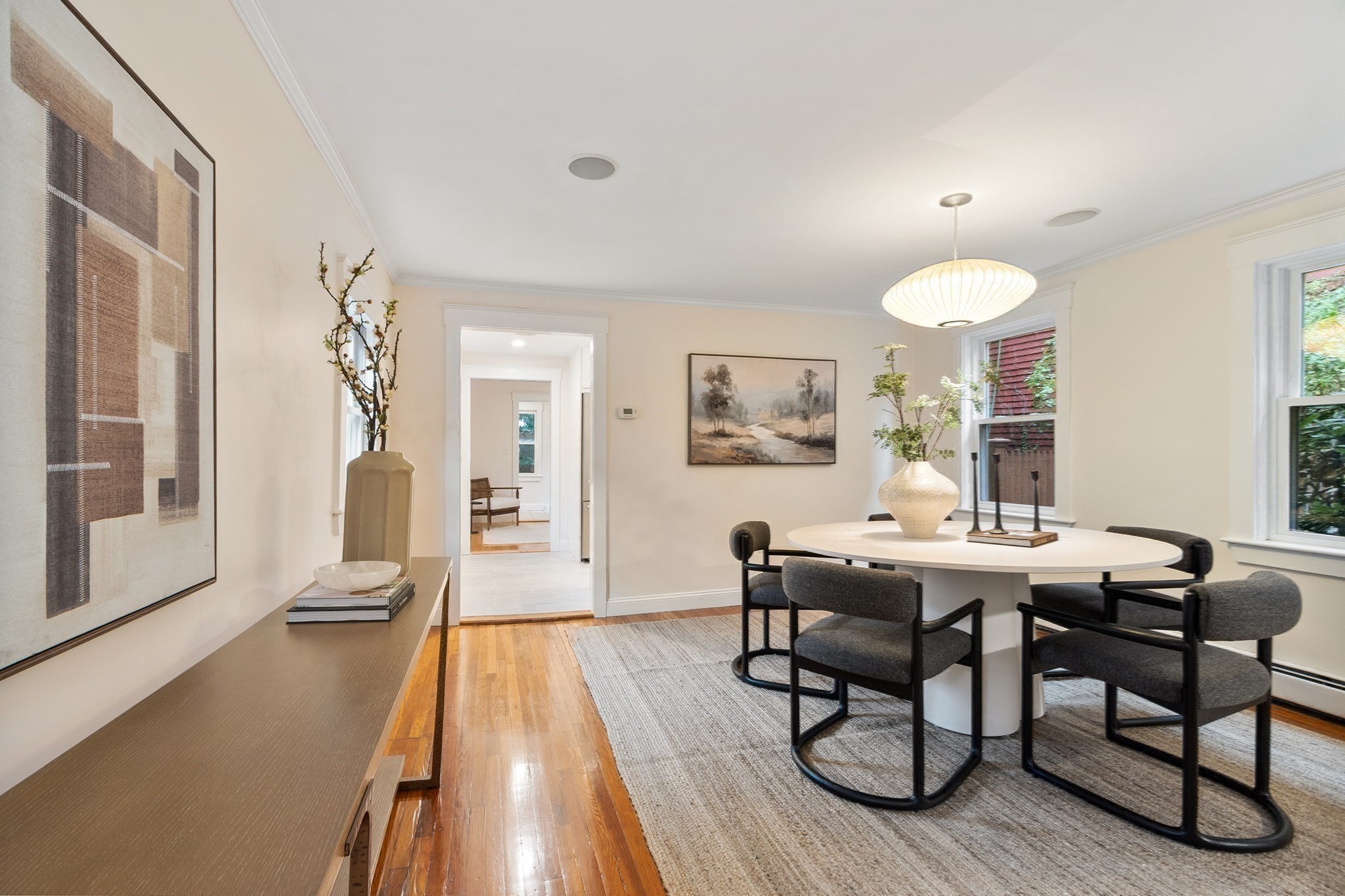 Staged dining room with an oval white table, dark chairs, and a glowing pendant light.