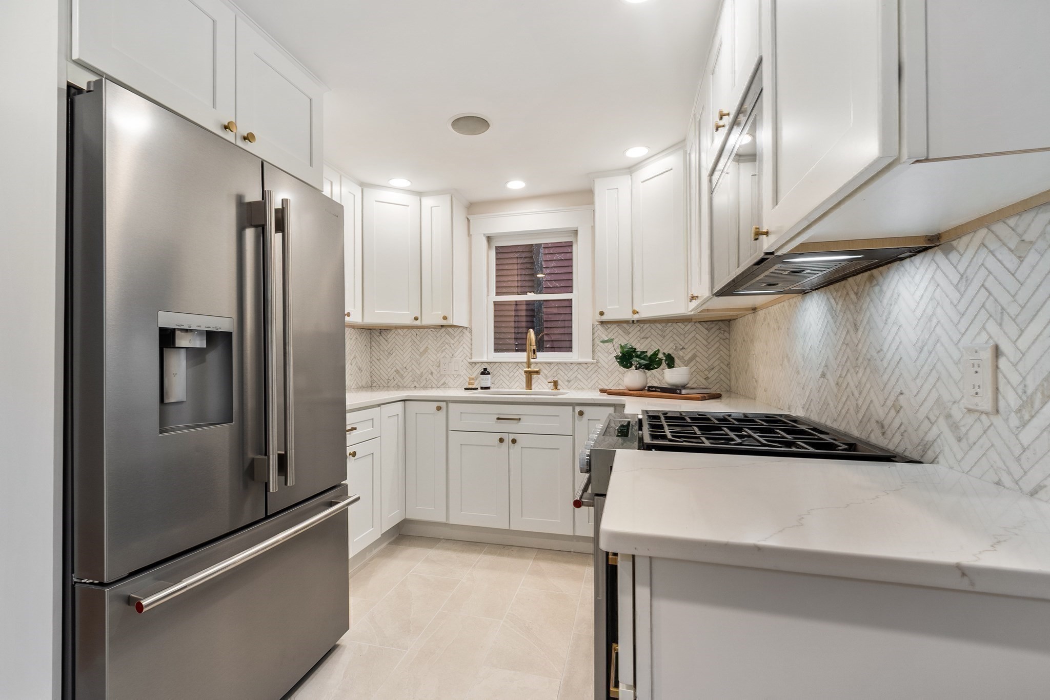 Kitchen with white cabinets, stainless steel appliances, and herringbone backsplash.