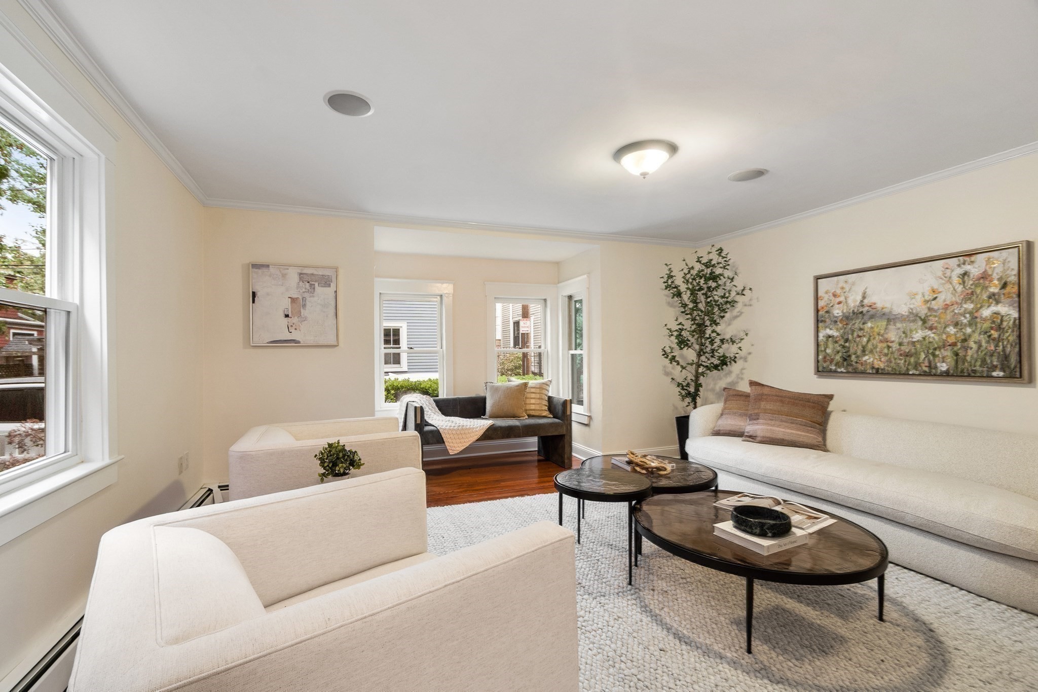 Staged living room with cream sofas, dark coffee tables, and windows overlooking the street.