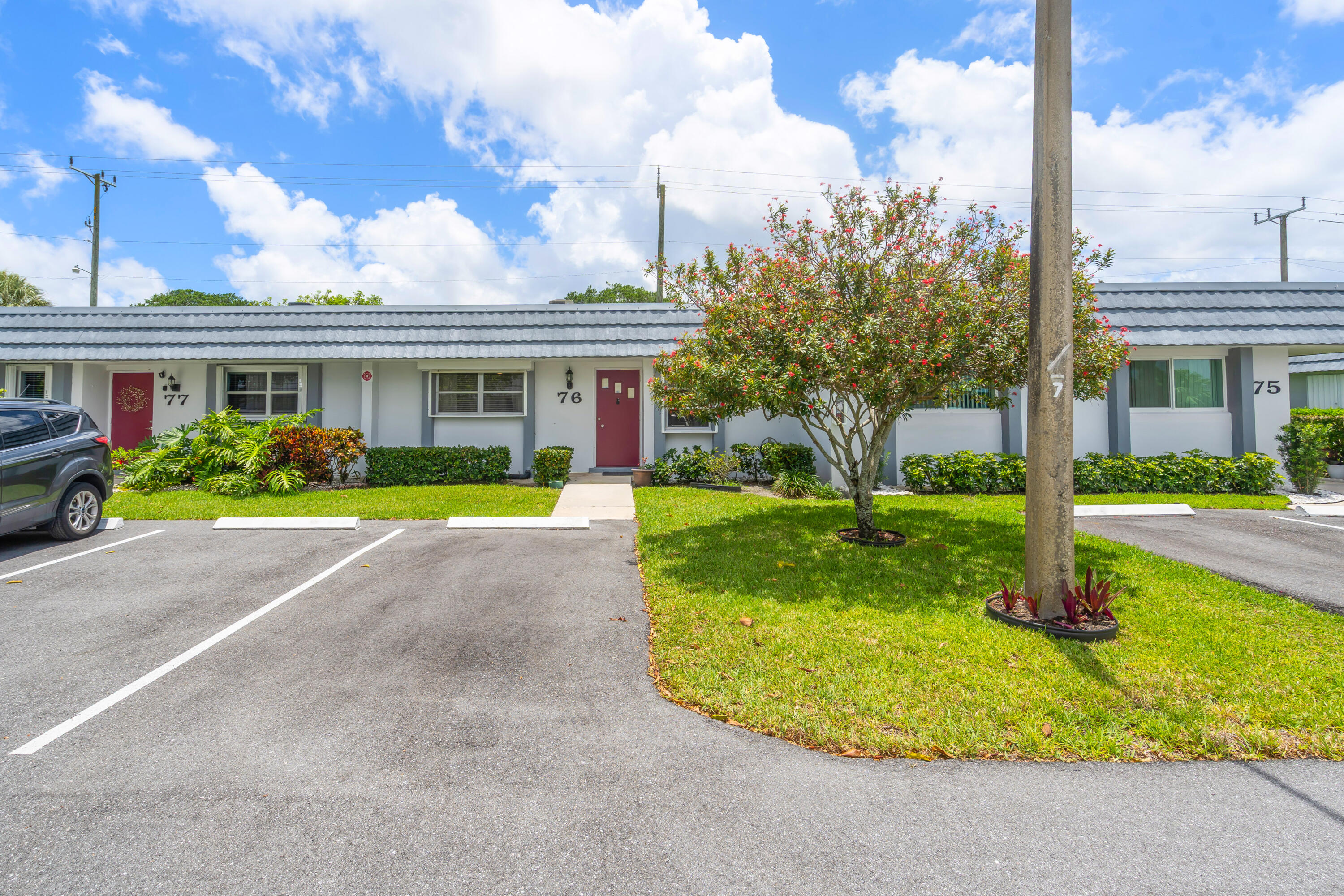 Single-story residences with red doors, front parking spaces, and a flowering tree.
